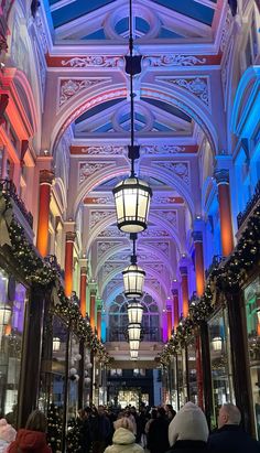 people are walking through an indoor mall with christmas decorations on the ceiling and lights hanging from the ceiling