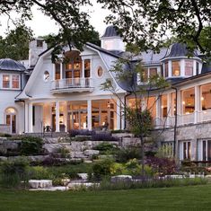 a large white house sitting on top of a lush green field