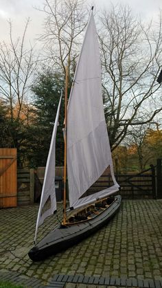 a small sailboat sitting on top of a brick walkway