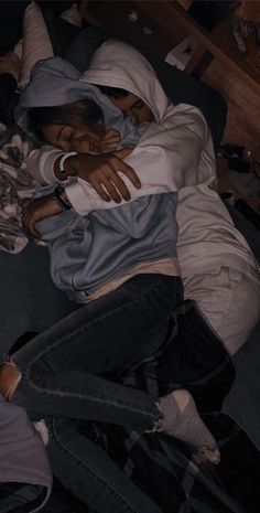 two people laying on a bed with their arms around each other