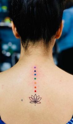 the back of a woman's neck with a colorful flower tattoo on her left shoulder