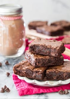 chocolate brownies stacked on top of each other in front of a jar of peanut butter