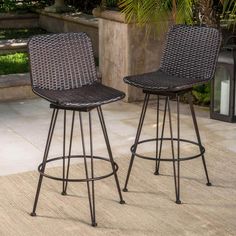 two brown wicker barstools sitting next to each other on top of a patio