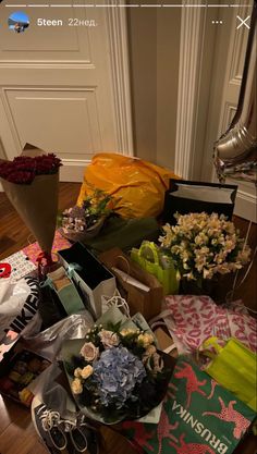 a bunch of flowers sitting on top of a wooden floor next to boxes and bags