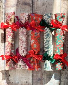 several wrapped presents are lined up on a wooden surface with red ribbons tied around them