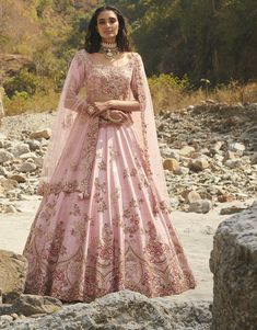 a woman in a pink gown standing on rocks