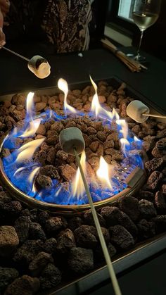 a person is cooking food on a grill with blue flames and marshmallows