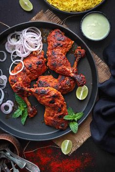 chicken with onions and cilantro on a black plate next to other food items