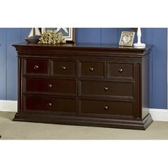 the dresser has many drawers in it and is dark brown with white trimmings