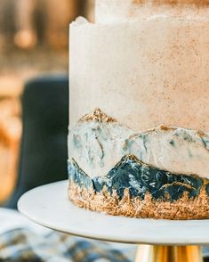 a three layer cake with frosting and mountains on the top is sitting on a plate