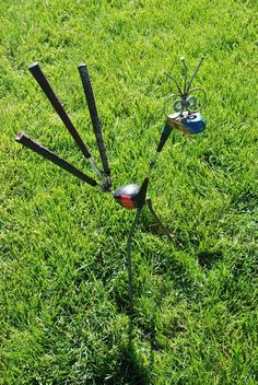 an upside down sculpture in the middle of some grass with scissors sticking out of it