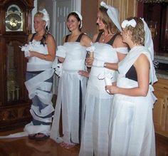 four bridesmaids in white dresses and veils are standing near a grandfather clock