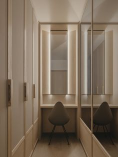 an empty dressing room with mirrors on the wall and two chairs in front of it