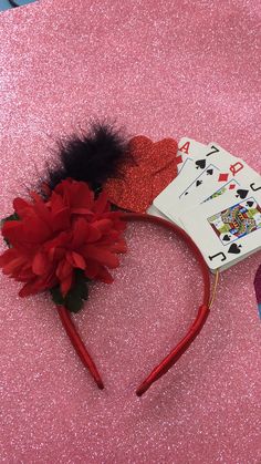 a pair of red and black hair clips on top of a pink table with playing cards