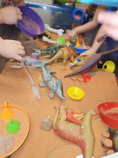 children are playing with plastic dinosaurs on the table