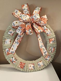 a wreath decorated with bows on top of a white shelf next to a brown wall