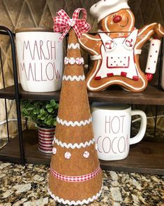 a wooden christmas tree sitting on top of a counter next to mugs and cookies