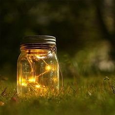 a mason jar filled with lights sitting in the grass