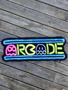 a patch with the word arcade written in neon colors and pacman faces on it