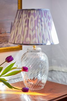 a lamp that is sitting on top of a table next to a vase with flowers in it