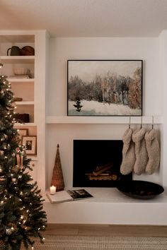 a christmas tree in front of a fireplace with stockings hanging from it's mantle