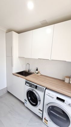 a washer and dryer in a small room with white cabinets on the walls