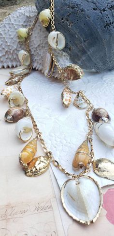 21 shells beautifully metal rimmed; Roget signed vintage necklace; 32 inches long; matching bracelet available. Bohemian Metal Shell Jewelry, Bohemian Shell Jewelry With Lobster Clasp, Vintage Gold Shell Jewelry, Bohemian Shell Necklace With Lobster Clasp, Vintage Long Necklace Jewelry For Beach, Gold Shell-shaped Bohemian Necklace, Vintage Gold Beach Jewelry, Vintage Gold Jewelry For Beach, Gold Bohemian Shell Necklace