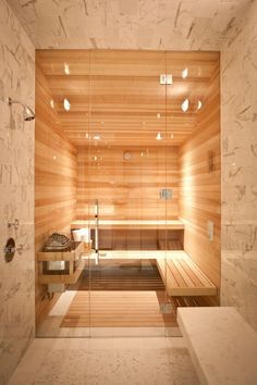 a sauna with wooden walls and benches in the middle is lit up by recessed lights