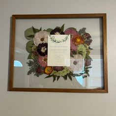 a frame with flowers on it and a paper card attached to the front of it