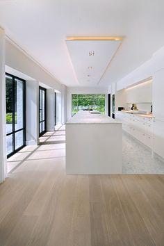 an empty kitchen with white cabinets and wood flooring is seen in this image from the hallway