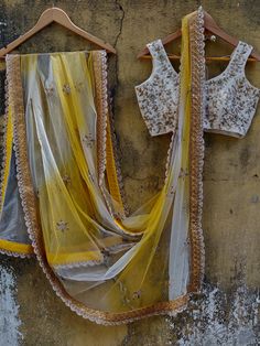 This ivory butti georgette lehenga is paired with an ivory embroidered raw silk blouse.  The outfit is complemented with a net yellow and ivory shaded dupatta with a scalloped border. White Lehenga With Intricate Embroidery In Tissue Silk, White Lehenga In Tissue Silk With Intricate Embroidery, White Tissue Silk Lehenga With Cutdana Details, White Tissue Silk Lehenga With Cutdana, White Pre-draped Saree With Gota Work For Navratri, White Semi-stitched Lehenga In Tissue Silk, Yellow Georgette Sets With Sheer Dupatta, White Anarkali Tissue Silk Choli, White Anarkali Choli In Tissue Silk