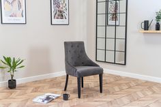 a grey chair sitting on top of a hard wood floor next to a potted plant