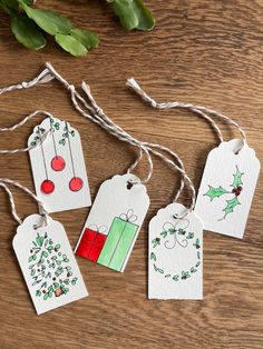 four christmas gift tags with holly and red berries on them hanging from twine string