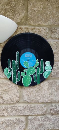 an old record with cactus decals on it next to a white vase and wall