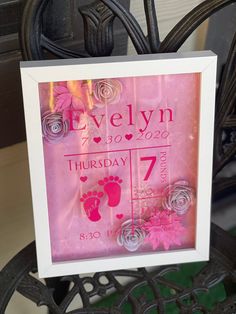 a baby's birth announcement is displayed in a frame on a chair with flowers