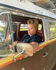 a young man sitting in the driver's seat of an old van