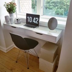 a laptop computer sitting on top of a white desk next to a window sill