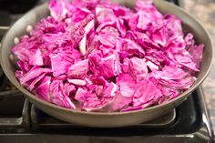 a pan filled with chopped red cabbage on top of a stovetop burner next to an oven