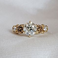 a close up of a diamond ring on a white surface with gold trimmings