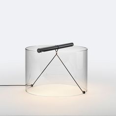 a glass table with a black object on it's side and a cord running through the middle