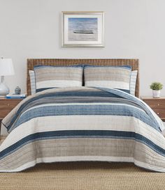 a bed with blue and white bedspread in a bedroom next to a nightstand