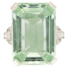 This Art Deco cocktail ring showcases a striking 18.52 carat emerald cut aquamarine at its centre, exuding a captivating green hue. The large green aquamarine is elegantly claw set within an open basket ensuring light pours through the stone, keeping it looking its best. Complementing the central gemstone are a total of 0.12 carats of eight cut diamonds, arranged in three diamonds per shoulder, adding a touch of sparkle to the ring. Crafted from 18 carat white gold, this 1940s ring exemplifies the opulence of Art Deco design. Gemstone: Aquamarine Stone Shape: Emerald Cut Carat Weight: 18.52 Metal: 18ct White Gold Age: 1920s Size: N Aquamarine Cocktail Ring, Art Deco Cocktail, Crossover Diamond Ring, Jewelry Knowledge, Green Aquamarine, Vintage Jewelry Art, Gold Art Deco, Diamond Cocktail Rings, Three Stone Engagement