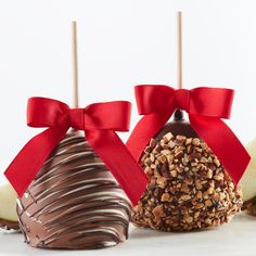 two chocolate covered apples with red bows on them