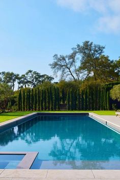 an empty swimming pool surrounded by trees and lawn chairs