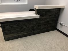 an empty reception area with white counter tops and black wood grained panels on the wall