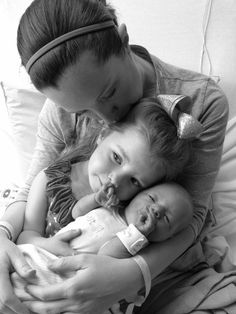 a black and white photo of a woman holding two babies