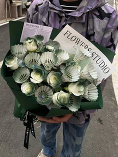 a person holding a bouquet of flowers and a book in their hands on the street