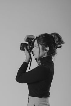 a woman holding a camera up to her face while she is taking a photo in the air