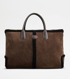 Tod's Di Bag in a refined winter version, with a shearling piping to replace the iconic central ribbing. Crafted in soft suede, with Tod's oval on the front, it features tubular handles in smooth leather and a removable shoulder strap in fabric. Complemented by an internal zipped pouch, it accompanies your everyday outfit with class. Everyday Outfit, Gift Boutique, Zip Pouch, Logo Stamp, Soft Suede, Trainers Women, Mens Trainers, Bago, Smooth Leather