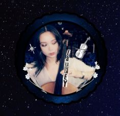 a woman holding a bass in her right hand and looking down at the ground with stars on it